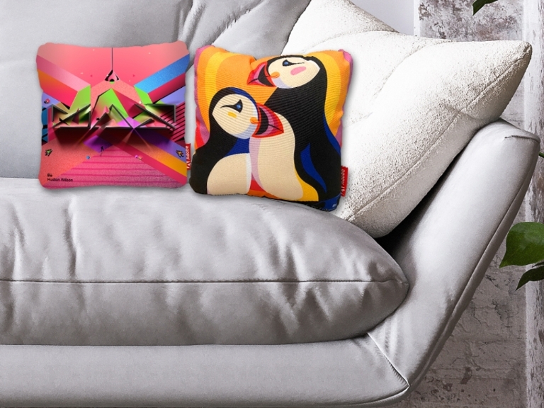 a white sofa with two colorful pillows, one with MAX logo